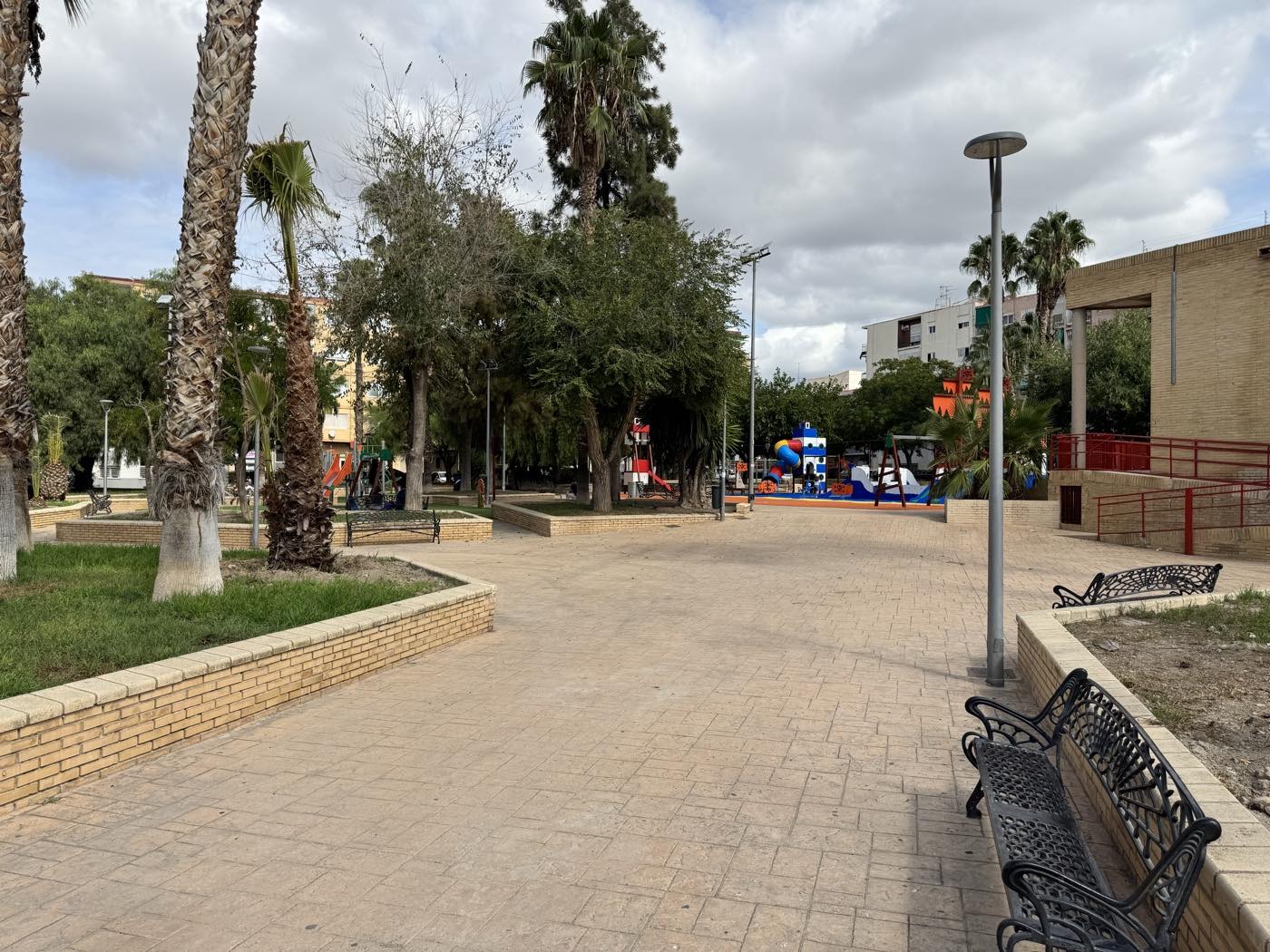 Plaza Nueva Fraternidad: paseo adoquinado con palmeras, bancos de forja y los juegos infantiles nuevos al fondo