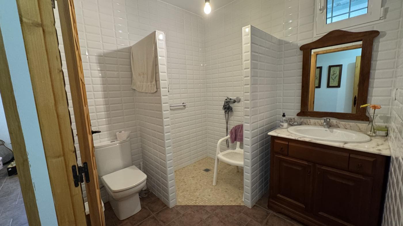 Baño con plato de ducha de obra y mueble de lavabo de madera