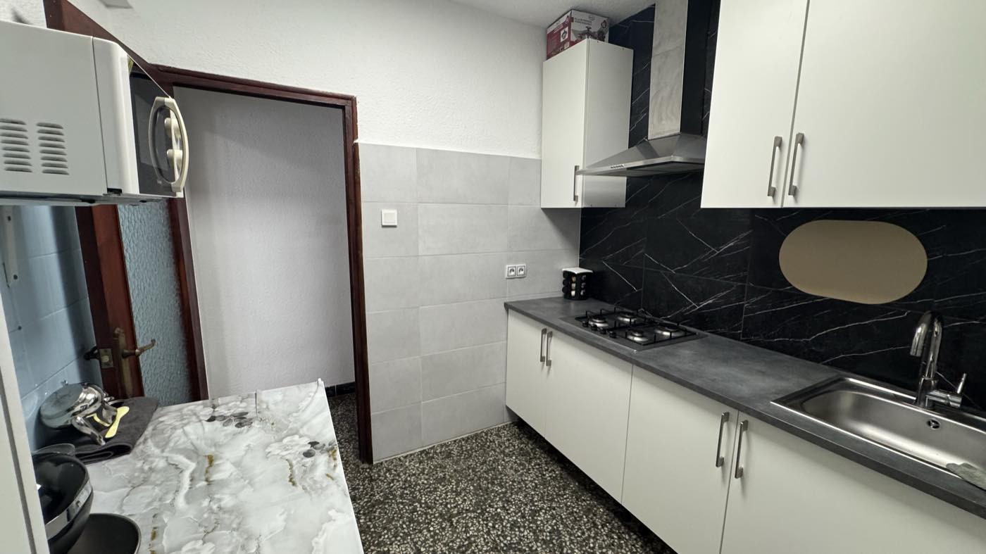 Otra vista de la cocina renovada, con fregadero bajo los muebles altos